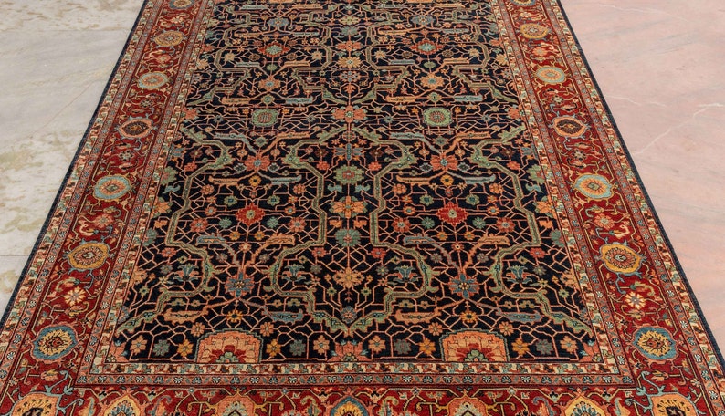 May include: A traditional Persian rug with a dark blue background and intricate floral patterns in shades of red, orange, and green. The rug has a wide border with a repeating design.