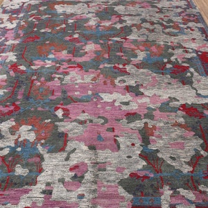 May include: A colorful abstract rug with shades of pink, red, blue, and gray. The rug has a distressed, vintage look and a unique, modern design.