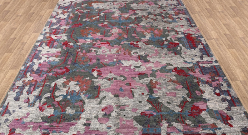 May include: A colorful abstract rug with shades of pink, red, blue, and gray. The rug has a distressed, vintage look and a unique, modern design.