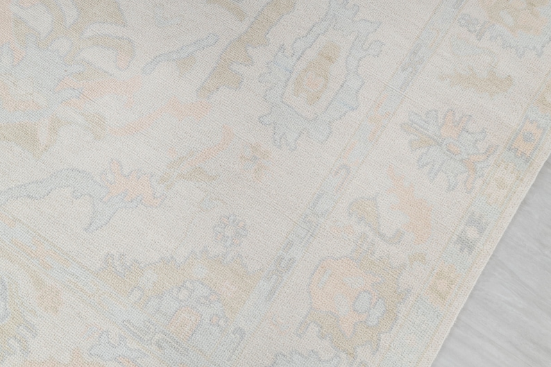 May include: A light beige rug with a subtle pattern of light blue and peach floral designs.