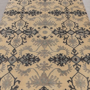 Puede incluir: Una alfombra beige con un patr&oacute;n geom&eacute;trico negro y gris. La alfombra tiene un dise&ntilde;o tradicional con detalles intrincados.
