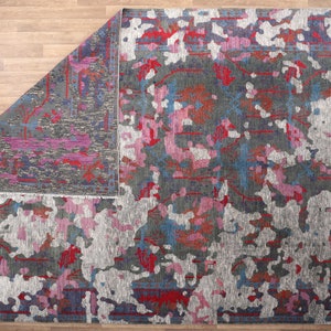 May include: A gray, pink, and blue abstract area rug with a distressed, faded look. The rug has a contemporary design with a mix of colors and textures.