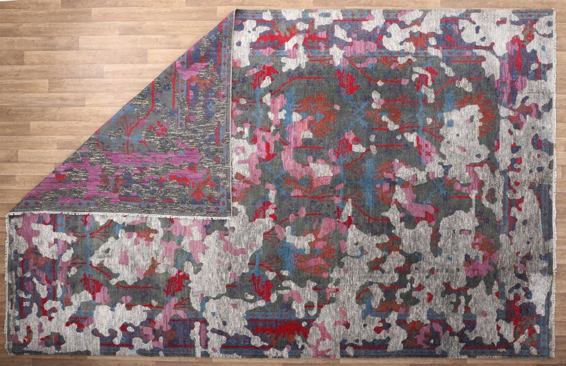 May include: A gray, pink, and blue abstract area rug with a distressed, faded look. The rug has a contemporary design with a mix of colors and textures.