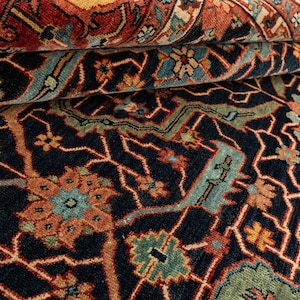 May include: Close-up of a dark blue rug with intricate patterns in shades of red, orange, green, and blue. The rug has a traditional Persian design with floral motifs and geometric shapes.