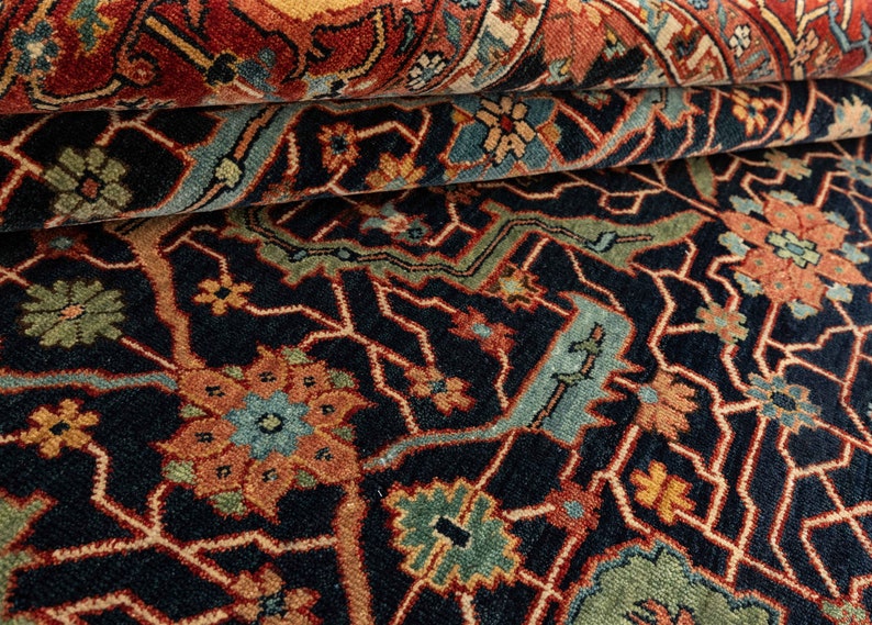 May include: Close-up of a dark blue rug with intricate patterns in shades of red, orange, green, and blue. The rug has a traditional Persian design with floral motifs and geometric shapes.