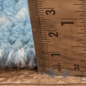 Puede incluir: Primer plano de una alfombra azul y blanca con una regla que mide 6,35 cm.