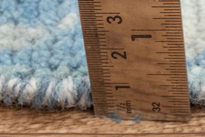 Puede incluir: Primer plano de una alfombra azul y blanca con una regla que mide 6,35 cm.