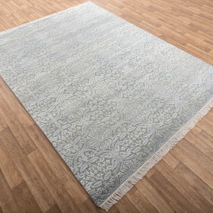 May include: A light blue rug with a white floral pattern. The rug has a fringe border.