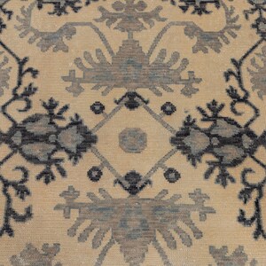 Puede incluir: Una alfombra beige con un patr&oacute;n repetitivo de dise&ntilde;os florales negros y azules. La alfombra tiene un dise&ntilde;o tradicional e intrincado.