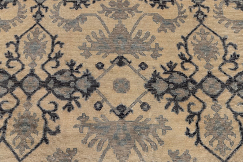 Puede incluir: Una alfombra beige con un patr&oacute;n repetitivo de dise&ntilde;os florales negros y azules. La alfombra tiene un dise&ntilde;o tradicional e intrincado.