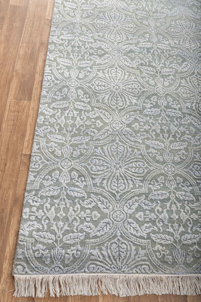May include: A light green rug with a white floral pattern and a fringe border.