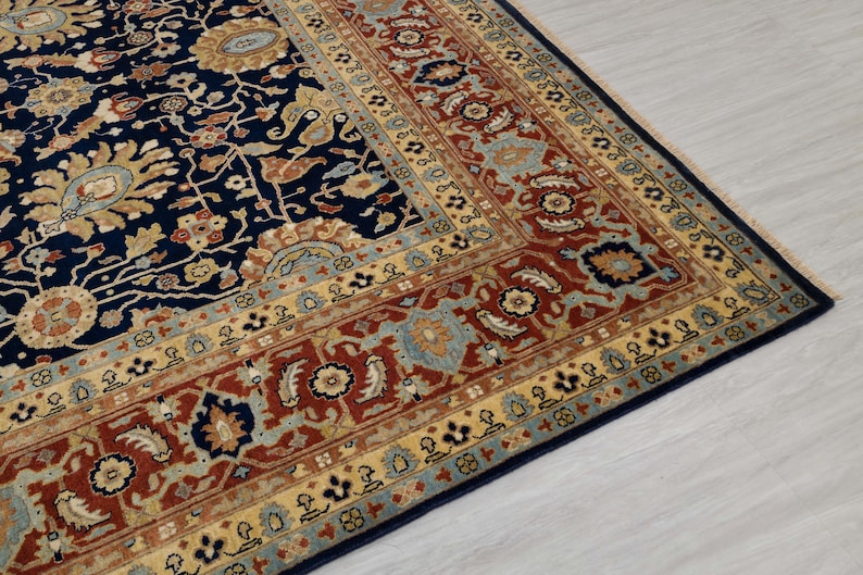 May include: A navy blue rug with a detailed floral pattern in shades of red, gold, and blue. The rug has a border with a repeating pattern of small flowers and leaves.