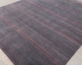 May include: A dark gray and pink patterned rug with a fringe border. The rug has a subtle herringbone pattern.