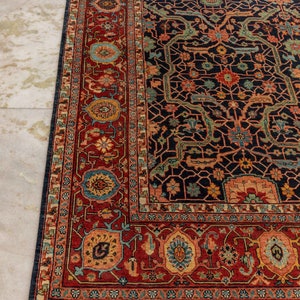 May include: A traditional Persian rug with a dark blue background and intricate floral patterns in shades of red, orange, and green. The rug has a white fringe border.