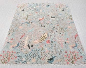 May include: A rectangular rug with a pale blue backdrop, adorned with a repeating design of birds, trees, and flowers in diverse colours. The rug has a fringed edge and is suitable for home decor.