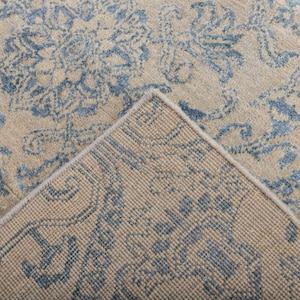 K&ouml;nnte beinhalten: Nahaufnahme der R&uuml;ckseite eines Teppichs mit einem blauen und beigen Muster. Der Teppich hat eine gewebte Textur und einen Fransenrand.