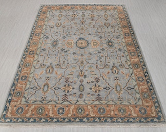 Könnte beinhalten: Ein blauer und brauner Teppich mit einem detaillierten floralen Muster. Der Teppich hat einen Fransenrand.
