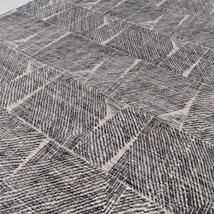 May include: A black and white patterned rug with a geometric design. The rug has a textured surface and is made of a woven material.