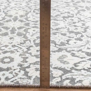 Może przedstawiać: Zbliżenie na dywan w biało-szary wz&oacute;r z linijką o długości 45,7 cm.