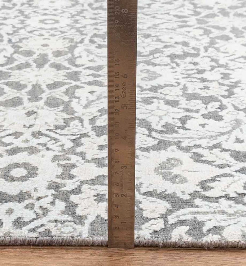 Może przedstawiać: Zbliżenie na dywan w biało-szary wz&oacute;r z linijką o długości 45,7 cm.