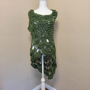 May include: A green crocheted shawl with a high-low hemline. The shawl is made with a delicate openwork stitch and has a flowing, asymmetrical design.