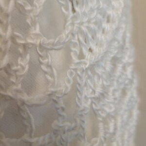 May include: White crochet fabric with a delicate, intricate pattern. The fabric is soft and airy, with a slightly textured surface.