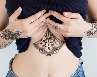 May include: A black tank top with lace trim is pulled up to reveal a black and white mandala tattoo on the stomach.