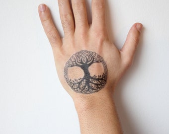 May include: A black and white temporary tattoo of a tree of life design on a person's hand.