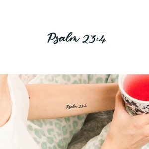 Könnte beinhalten: Ein Arm mit einem temporären Tattoo, auf dem "Psalm 23:4" in schwarzer Tinte steht.