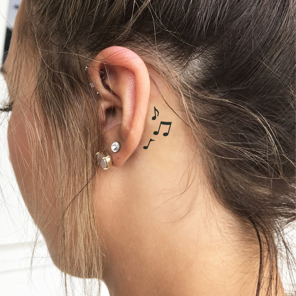 Small behind the ear matching tattoo of a treble clef