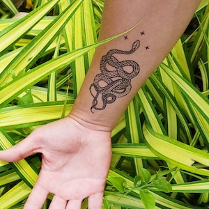 May include: A temporary tattoo of a black snake with stars on a person's arm.