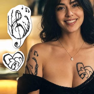 Puede incluir: Un conjunto de dos tatuajes temporales con diseños en tinta negra. Un tatuaje representa una clave de sol estilizada con notas musicales, y el otro muestra una forma de corazón con líneas abstractas en su interior, aplicados sobre la piel.
