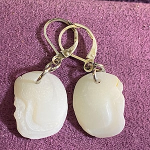 May include: A pair of white, opaque, teardrop-shaped earrings with silver hooks.