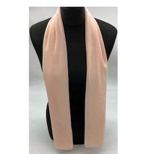 May include: A pale pink chiffon scarf draped over a mannequin.