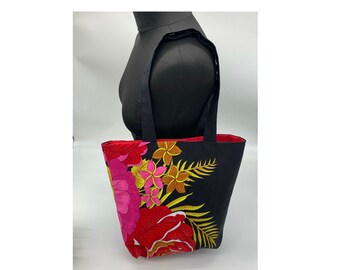 May include: A black tote bag with a floral design. The bag has red, pink, yellow, and gold flowers on a black background. The bag has two black straps.