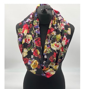 May include: A black infinity scarf with a floral print featuring red, yellow, white, and blue flowers.