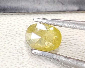 May include: A yellow oval-shaped diamond with a faceted cut. The diamond is held by tweezers.