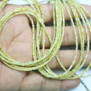 May include: A strand of yellow diamond beads, each bead is a small square shape. The beads are strung on a thin wire and are arranged in a loose, flowing pattern.