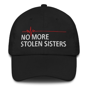 Puede incluir: Gorra de béisbol negra con un gráfico de latido del corazón rojo y el texto "NO MORE STOLEN SISTERS" en blanco.