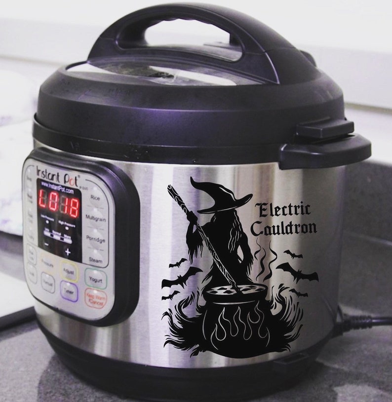 May include: A stainless steel Instant Pot electric pressure cooker with a black and white decal of a witch stirring a cauldron with bats flying around it. The decal reads "Electric Cauldron".