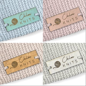 Könnte beinhalten: Vier farbige Holzetiketten mit dem Text "Chloe Knits" und einer kleinen Garnkugelgrafik. Die Etiketten befinden sich auf verschiedenen Strickstoffen.