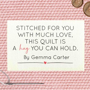 Może przedstawiać: Prostokątna etykieta z napisem "STITCHED FOR YOU WITH MUCH LOVE, THIS QUILT IS A hug YOU CAN HOLD. By Gemma Carter" na różowym tle z tkaniny. Widoczna igła i nić.
