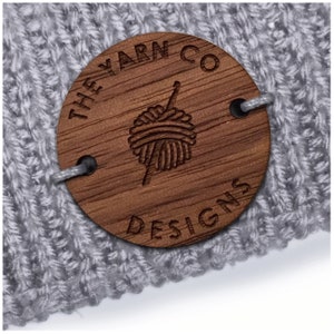 May include: A round wooden tag with the text "They Yarn Co Designs" and a stylized image of a ball of yarn and knitting needle.