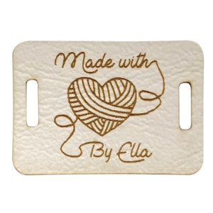 May include: White leather tag with a brown heart-shaped yarn ball and the text "Made with" above and "By Ella" below.