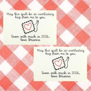 Może przedstawiać: Dwie kremowe etykiety z tekstem i wzorem naszywki w kształcie serca. Tekst brzmi: „Niech ten kołdrę będzie wiecznym uściskiem ode mnie dla ciebie” i „Szyte z dużą ilością w 2026 roku, love Brianna”. Tło to czerwono-biały wzór w kratę.