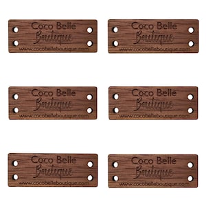 May include: Six wooden tags with the text "Coco Belle Boutique" and the website address "www.cocobelleboutique.com" engraved on them. The tags have four holes each.
