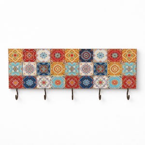 Könnte beinhalten: Ein dekorativer, an der Wand befestigter Schlüsselhalter mit einem farbenfrohen Fliesenmuster. Die rechteckige Holzplatte zeigt ein Muster aus quadratischen Fliesen in Rot, Blau, Gelb und Türkis. Vier schwarze Metallhaken sind unten angebracht.