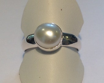 May include: A silver ring with a white pearl set in the center.