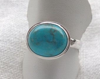 Op de afbeelding: Een zilveren ring met een ovale turquoise edelsteen gezet in een bezel setting.