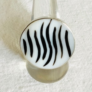 Può includere: Un anello d'argento con un motivo a zebre bianco e nero sulla superficie.